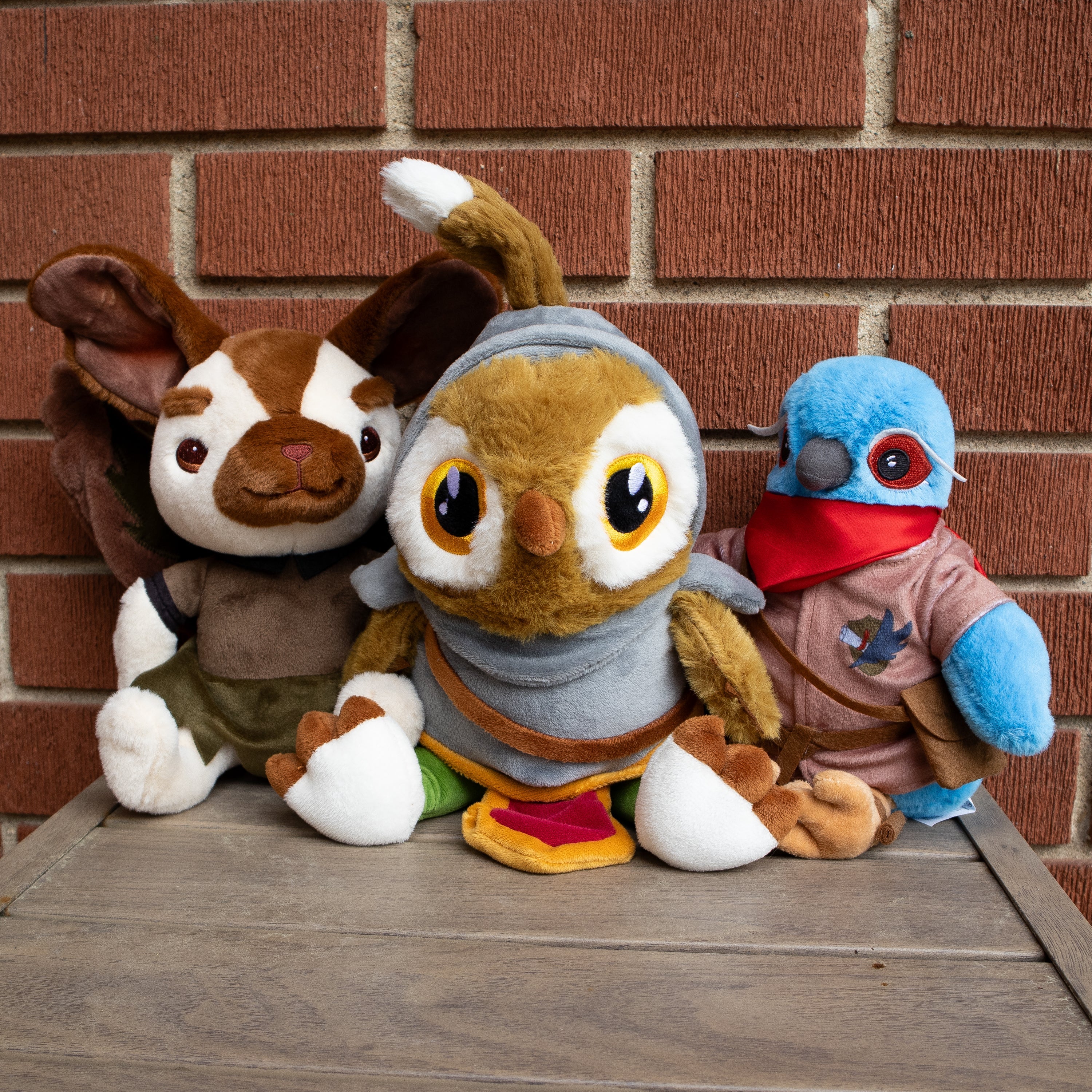 Three plush toys in front of a brick wall